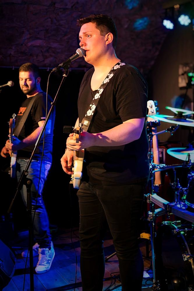 Simon Lautenschlager als Frontmann mit Band auf der Bühne